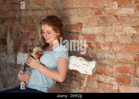 Teenager-Mädchen auf Bank mit Hund, Lächeln Stockfoto