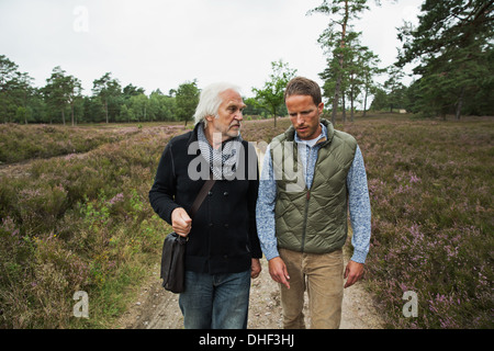 Vater und erwachsener Sohn zu Fuß auf Feldweg Stockfoto