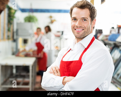 Glücklich Metzger stehend Arme verschränkt im Store Stockfoto