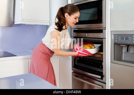 Junge Frau Bräter aus dem Ofen nehmen Stockfoto