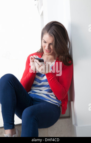Junge Frau sitzt auf Schritt mit Handy