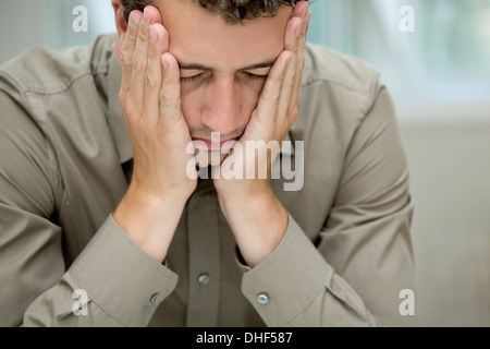 Junger Mann für Wangen mit Händen Stockfoto