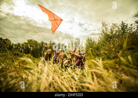 Fünf junge Frauen, die Spaß mit Drachen im Buschland Stockfoto