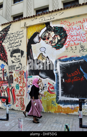 Zwei junge einheimische Frauen gehen 2012, ein Jahr nach der Revolution von 2011, an Graffiti auf der Mohamed Mahmoud Street nahe dem Tahrir-Platz in Kairo vorbei. Stockfoto