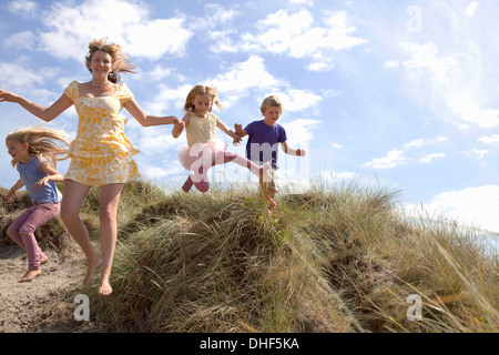 Mutter mit drei Kindern abspringen Dünen, Wales, UK Stockfoto