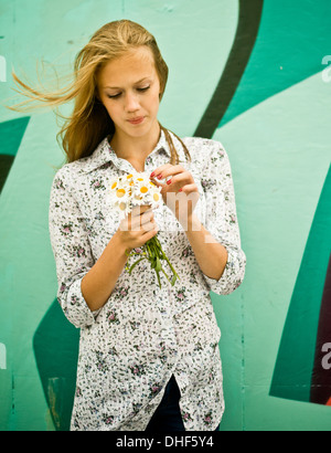 Porträt der jungen Frau mit Haufen von Gänseblümchen Stockfoto