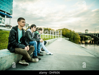 Vier Freunde sitzen auf Sichtbeton Wand, Russland Stockfoto