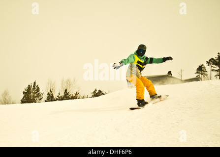 Junger Mann Snowboarden am Berg Stockfoto