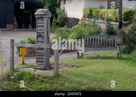 Holzbank und Wasserpumpe im Dorf Kersey in Suffolk. Stockfoto