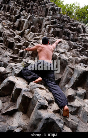 Ein Mann klettert barfuß in Los Ladrillos eine Basaltwand aus Felsen, die durch vulkanische Aktivität in der Provinz Boquete Republik Panama verursacht wird Stockfoto