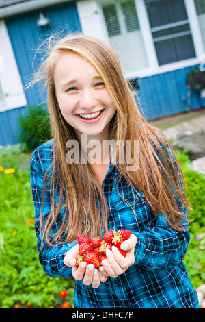 Porträt von lächelnden jungen Mädchen mit langen blonden Haaren hält frisch gepflückt Erdbeeren in ihren Händen Stockfoto