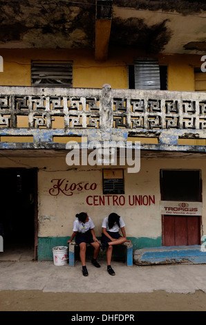 Die Schülerinnen auf der Straße sitzen in Carti Sugtupu Island Village durch Guna Eingeborenen als Kuna in der "Comarca" (Region) der Guna Yala im Archipel von San Blas Blas Inseln im Nordosten von Panama mit Blick auf das Karibische Meer bekannt gegeben. Stockfoto