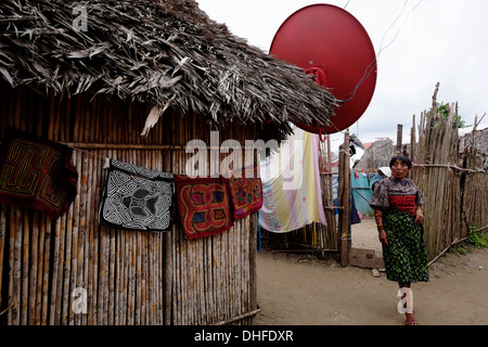 Eine Frau aus dem Guna Menschen zeigt eine Auswahl an traditionellen handgemachten Molas zum Verkauf an ihrem Haus in Carti Sugtupu Island Village durch Guna Eingeborenen als Kuna in der "Comarca" (Region) der Guna Yala im Archipel von San Blas Blas Inseln im Nordosten von Panama mit Blick auf das Karibische Meer bekannt gegeben. Stockfoto