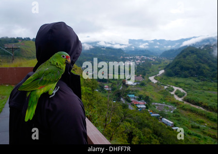 Mann mit Papagei auf der Schulter und Blick auf die kleine Bergstadt Boquete in der westlichsten Provinz Chiriquí im grünen Berghochland der Republik Panama Stockfoto