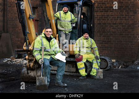 Drei Arbeiter vor Ort posiert auf ihrem JCB Bagger Stockfoto