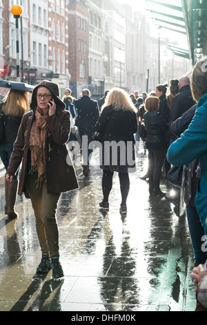 LONDON, UK - NOVEMBER 02: Belebte Straße außerhalb Covent Garden Station, mit Sonne Hintergrundbeleuchtung Fußgänger nach dem Regen. Stockfoto