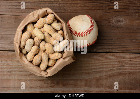 Eine Tasche von Erdnüssen und einen Baseball auf einer alten Holzbank im Stadion. Querformat mit Textfreiraum. Stockfoto