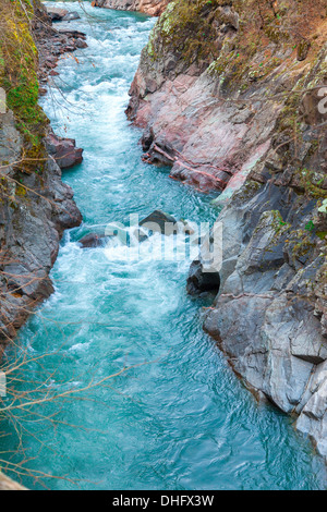 Gebirgsbach fließt durch die roten Felsen Stockfoto