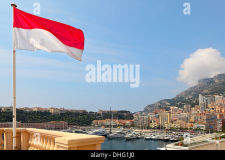 Nationalflagge, modernen Wohnbauten und Luxus-Yachten im Hafen Hercule unter blauem Himmel in Monte Carlo, Monaco. Stockfoto