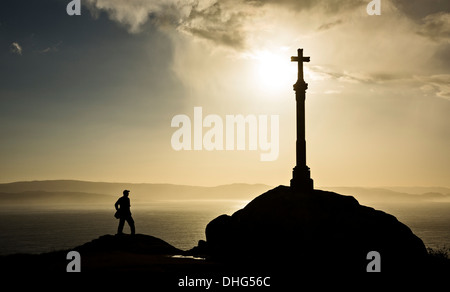 Eine Silhouette eines Mannes und Kreuz am Kap Finisterre in Galicien, Spanien. Stockfoto