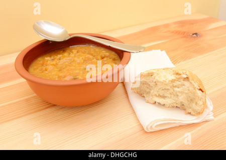 Löffel ruht auf einen Teller Suppe, mit einer halben Semmel auf eine serviette Stockfoto