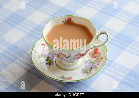 Eine Tasse Milchtee auf einem karierten Tischdecke. Stockfoto