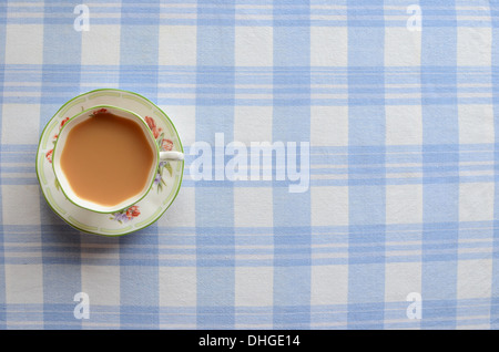 Eine Tasse Milchtee auf einem karierten Tischdecke. Stockfoto