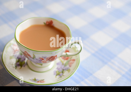 Eine Tasse Milchtee auf einem karierten Tischdecke. Stockfoto