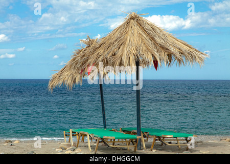 Sonnenliegen und Sonnenschirme mit Blick auf das Mittelmeer, auf Geropotamos Strand in der Nähe von Rethymnon, auf der Insel Kreta, Griechenland. Stockfoto