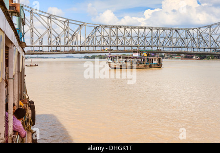 Öffentliche Fähren verkehren am Hoogly-Fluss mit der alten Howrah Bridge im Hintergrund in Kolkata, Indien. Stockfoto