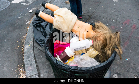 traurig goldenen Haaren Plastikpuppe aufgegeben in Abfalleimer mit Kaffeetassen & andere Detritus auf East Houston Street New York City Stockfoto