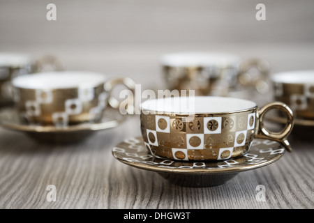 Verschiedenen goldenen türkischen Kaffeetassen sind auf einem hölzernen Hintergrund gesäumt. Stockfoto