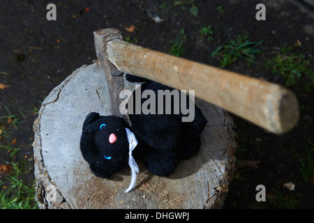 Ausführung - Mord an Kind Kuscheltier schwarze Katze mit einer Axt Stockfoto