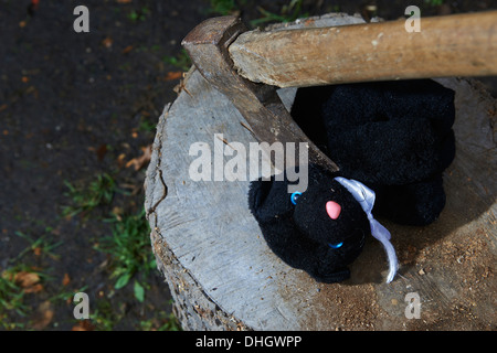 Ausführung - Mord an Kind Kuscheltier schwarze Katze mit einer Axt Stockfoto