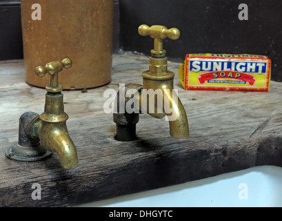 Zwei alte historische viktorianische Messing-Armaturen, Hebel Sunlight-Seife über einem Waschbecken Belfast in England, UK Stockfoto