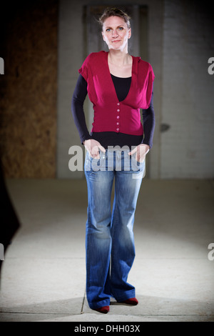 Schlanke zufrieden Frau steht mit den Händen in den Taschen der Jeans, jahrelange Ballett zeigen ihre Wirkung nicht verkleidet. Stockfoto