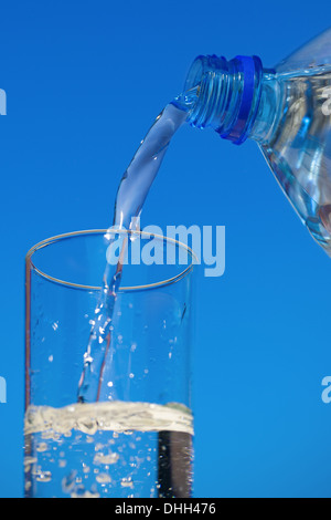 Das Wasser fließt aus der Flasche in ein Glas