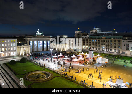 Berlin, Deutschland. 10. November 2013. Leute betrachten Projektionen auf dem Brandenburger Tor zeigt Porträts von Menschen, die während des NS-Regimes in Berlin, Deutschland, 10. November 2013 verfolgt. Das Themenjahr "Vielfalt - zerstört 1933-1938 - 1945" mit der Projektion von Videos endet funktioniert durch Jugendliche, Porträts der verfolgten Künstler während des NS-Regimes, Gespräche mit Zeitzeugen und Konzerte am Pariser Platz in Berlin, Deutschland, 10. November 2013. Foto: Florian Schuh/Dpa/Alamy Live News Stockfoto