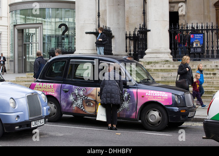 Eine Frau, die Einstellung einer berühmten Black Cab in London England Stockfoto