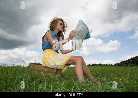 Teenager-Mädchen sitzen auf Koffer lesen Karte Stockfoto