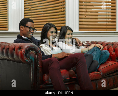 Drei junge Erwachsene Freunde Zusammensitzen auf sofa Stockfoto