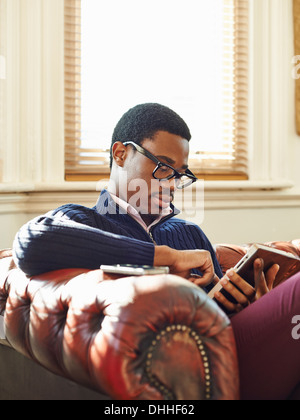 Junger Mann auf Sofa lesen Stockfoto