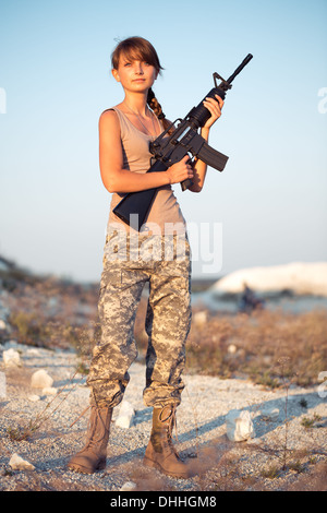 Junge schöne Soldatin, gekleidet in eine Tarnung mit einem Gewehr in der Lage Stockfoto