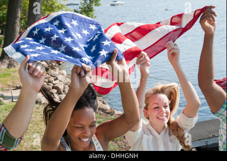 Freunde mit US-Flagge über Köpfen, Lächeln Stockfoto