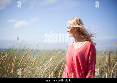 Porträt von blonde Frau trägt rosa Pullover in Dünengebieten Grass, Wales, UK Stockfoto