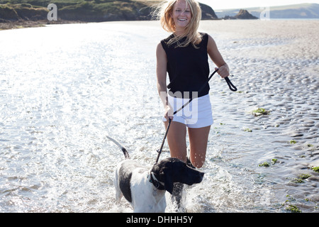 Frau zu Fuß Hund am Strand, Wales, UK Stockfoto