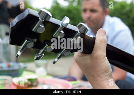 Nahaufnahme von Gitarre, Mann im Hintergrund Stockfoto