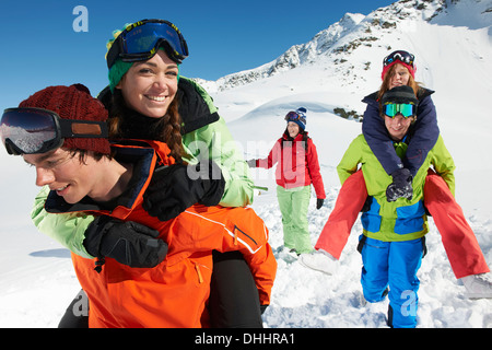 Männer geben Frauen Schweinchen im Schnee, Kühtai, Österreich sichert Stockfoto