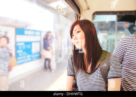 Junge Frau am Bahnhof, Blick durch Fenster Stockfoto