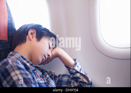 Junge schlafend auf Flugzeug Stockfoto